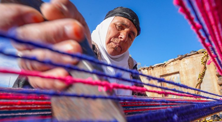 Evinin bahçesindeki tezgahta asırlık yöntemle kilim dokuyor